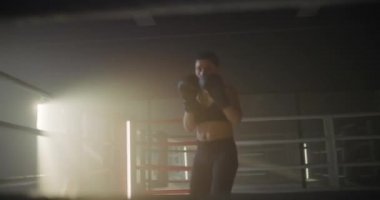 Boks ringinde boks yapan kadın. Kadın Dövüşçü Karanlık Yüzük 'te Yumruk ve Kamera' ya Bakıyor. Kadın Kickboksör Portresi. Boks Konsepti.