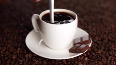 Beyaz bir fincan kahve kahve çekirdekleri bir kaşıkla üzerine şekeri önlemek