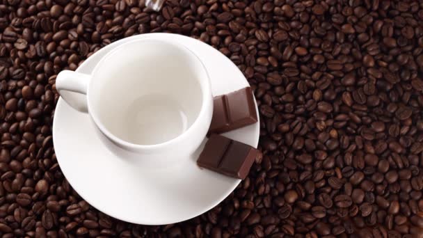 Café versé dans une tasse blanche sur les grains de café — Video