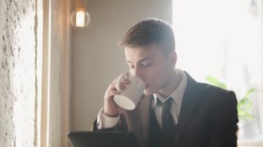 Portre yakışıklı başarılı adam kahve içmek ve tablet'bir görünüm