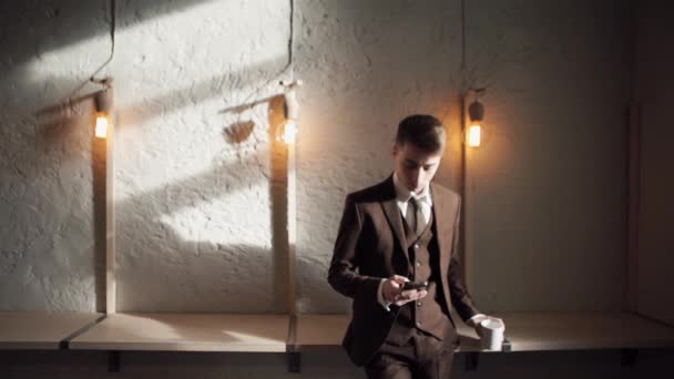 कॅफेमध्ये मोबाइल फोन वापरणारा माणूस आनंदी हिप्स्टर आहे आणि कॉफी पितो — स्टॉक व्हिडिओ