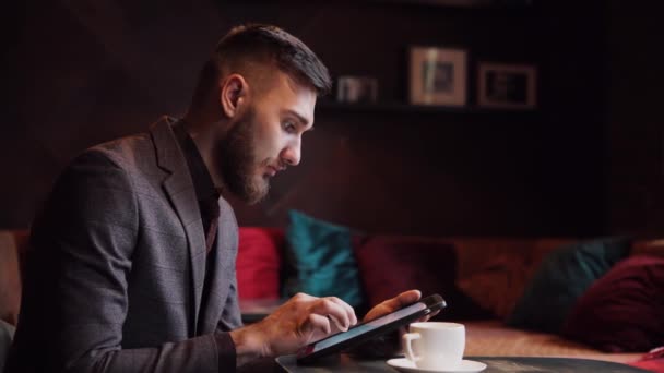 Blbeček bederní chlap sedí u baru tabulky a pomocí tablet — Stock video