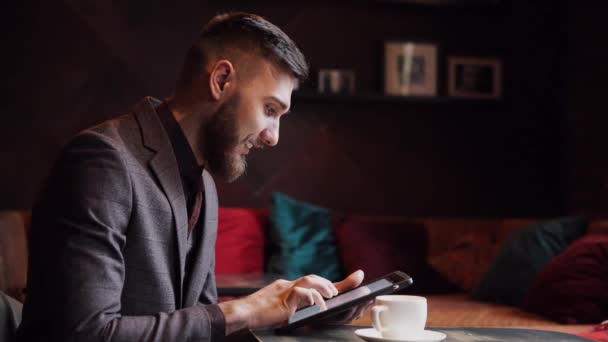 Nörd hipster kille sitter på bar bord och använder en Tablet PC — Stockvideo