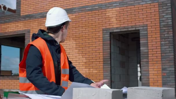 Arquitecto mirando planos en un sitio de construcción — Vídeo de stock