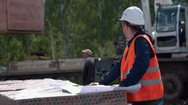 Architect kijken naar blauwdrukken in een bouwterrein — Stockvideo