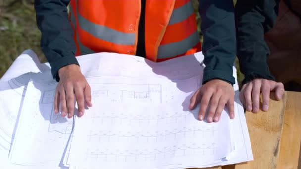 Arquiteto olhando para plantas em um canteiro de obras — Vídeo de Stock