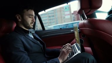 Arabanın arkasında çalışan ve bir tablet kullanarak iş adamı
