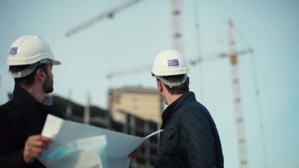 Ingeniero y cliente mirando el proyecto en el sitio de construcción — Vídeo de stock