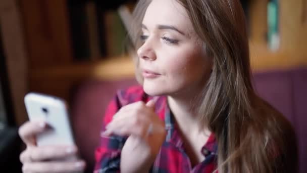 Relajante después de un largo viaje. Vista superior de la hermosa mujer joven en ropa de cabeza acostada en el suelo sosteniendo el teléfono móvil y sonriendo — Vídeos de Stock