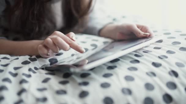 Vrouw in bed liggen met digitale tablet met vinger aanraken. Van bovenaf bekijken — Stockvideo