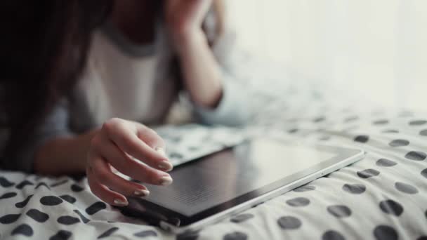 Mujer acostada en la cama con la tableta digital tocando con el dedo. Vista desde arriba — Vídeo de stock