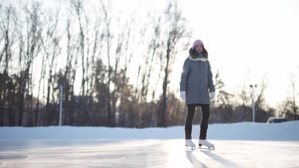 Mujer joven patinando sobre hielo con patines de figuras al aire libre en la nieve — Vídeos de Stock