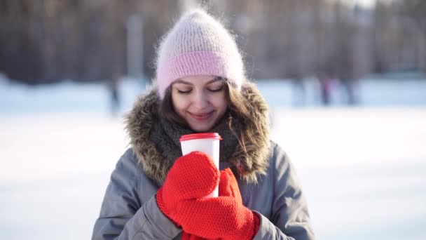 Menina com caneca de bebida quente na pista de patinação no gelo — Vídeo de Stock