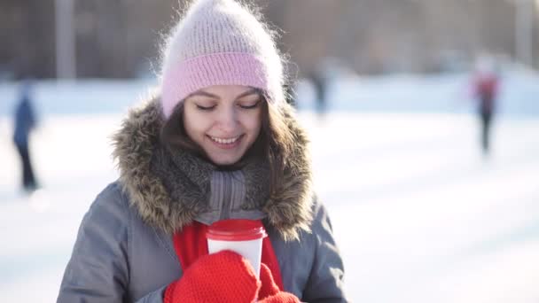 Girl with mug of hot drink on ice skating rink — Stock Video