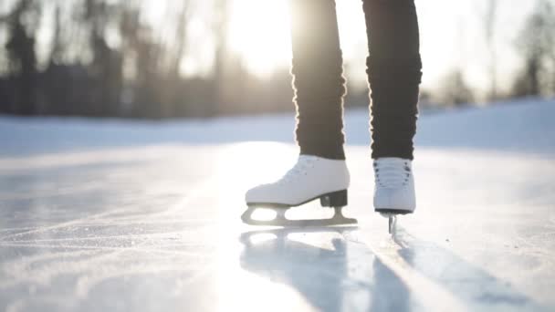 Mujer joven patinando sobre hielo con patines de figuras al aire libre en la nieve — Vídeo de stock