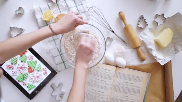Kvinna med tablet pc-dator att göra pepparkakor hus hemma — Stockvideo