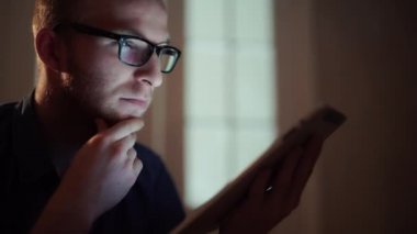 tablet ile oturma odasında kanepede uzanmış gece çalışan adam.