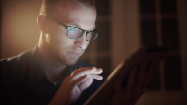 Man aan het werk nachts op sofa in de woonkamer met tablet liggen. — Stockvideo