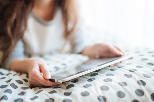 Mulher deitada na cama com tablet digital tocando com o dedo . — Fotografia de Stock