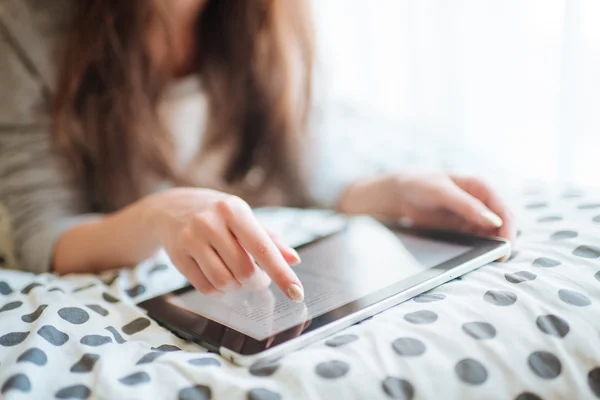 Vrouw in bed liggen met digitale tablet met vinger aanraken. Van bovenaf bekijken — Stockfoto