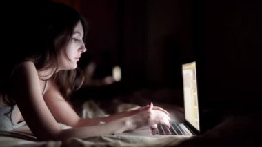 mutlu genç kadın yatakta yatarken laptop ile. beyaz izole