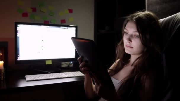 Девочка-подросток смотрит кино на планшете в постели ночью — стоковое видео