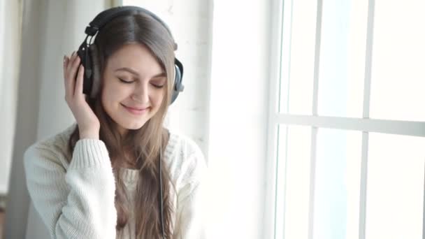 Mujer escuchando música en auriculares sobre fondo alféizar de ventana — Vídeo de stock