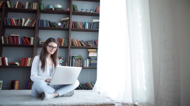 Mujer hermosa joven feliz usando el ordenador portátil, en interiores — Vídeo de stock