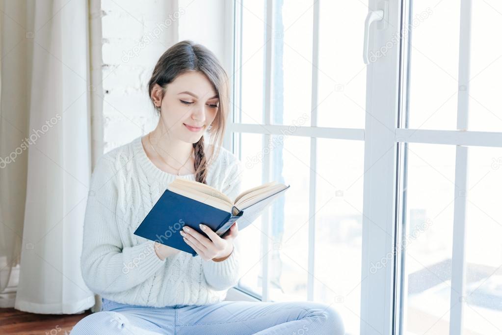 Young woman at home reading book