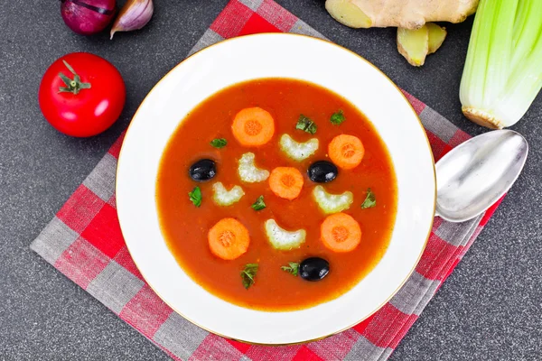 Морквяний томатний суп у тарілці. Позаду лежать інгредієнти супу , — стокове фото
