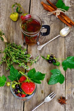 Çilek, Siyah frenk üzümü ve ahşap rustik zemin üzerine çay