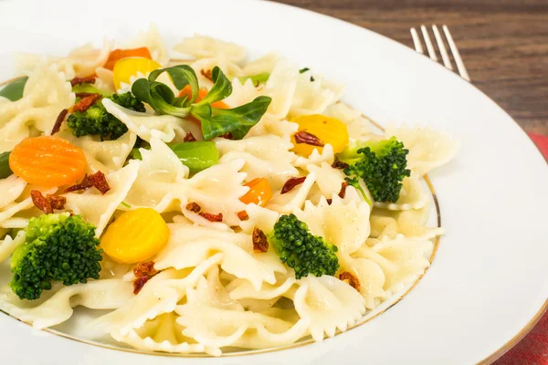 Farfalle con zanahorias, frijoles, brócoli y salchichas — Foto de Stock