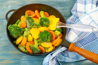 Vejetaryen yemeği. Mavi ahşap arka planda kızarmak için dondurulmuş taze sebzelerin karışımı..