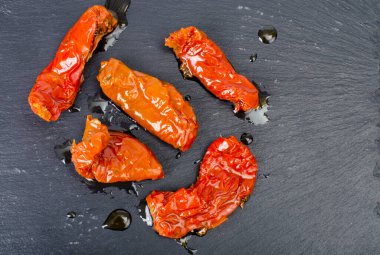 Siyah taş zemin üzerinde güneşte kurutulmuş lezzetli domatesler. Stüdyo Fotoğrafı