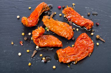 Siyah taş zemin üzerinde güneşte kurutulmuş lezzetli domatesler. Stüdyo Fotoğrafı