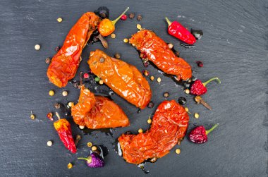 Siyah taş zemin üzerinde güneşte kurutulmuş lezzetli domatesler. Stüdyo Fotoğrafı