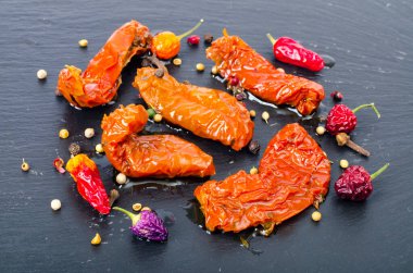 Siyah taş zemin üzerinde güneşte kurutulmuş lezzetli domatesler. Stüdyo Fotoğrafı