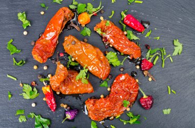 Siyah taş zemin üzerinde güneşte kurutulmuş lezzetli domatesler. Stüdyo Fotoğrafı