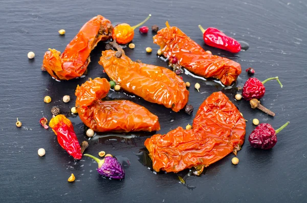 Siyah taş zemin üzerinde güneşte kurutulmuş lezzetli domatesler. Stüdyo Fotoğrafı