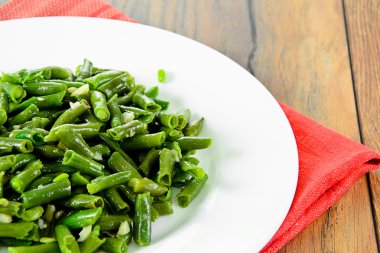 Beyaz bir plaka üzerinde sarımsaklı kızarmış yeşil fasulye