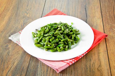 Beyaz bir plaka üzerinde sarımsaklı kızarmış yeşil fasulye