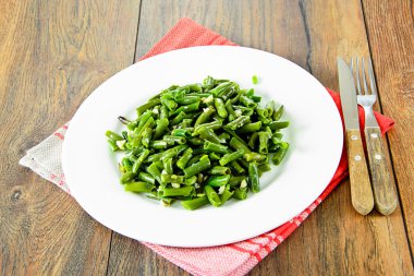 Beyaz bir plaka üzerinde sarımsaklı kızarmış yeşil fasulye