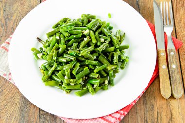 Beyaz bir plaka üzerinde sarımsaklı kızarmış yeşil fasulye