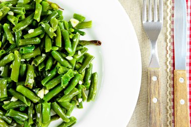 Beyaz bir plaka üzerinde sarımsaklı kızarmış yeşil fasulye