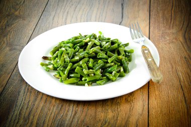 Beyaz bir plaka üzerinde sarımsaklı kızarmış yeşil fasulye