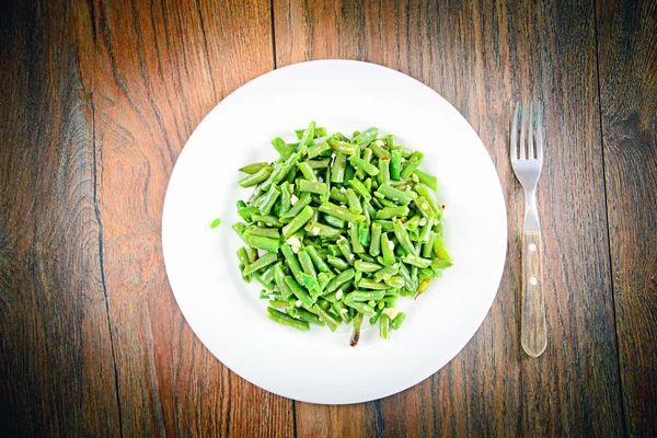 Haricots verts frits à l'ail sur une assiette blanche — Photo