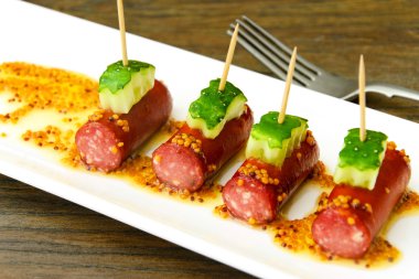 Kokteyl sosisi ve salatalık plaka üzerinde.