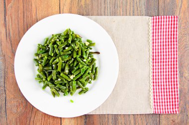 Beyaz bir plaka üzerinde sarımsaklı kızarmış yeşil fasulye.