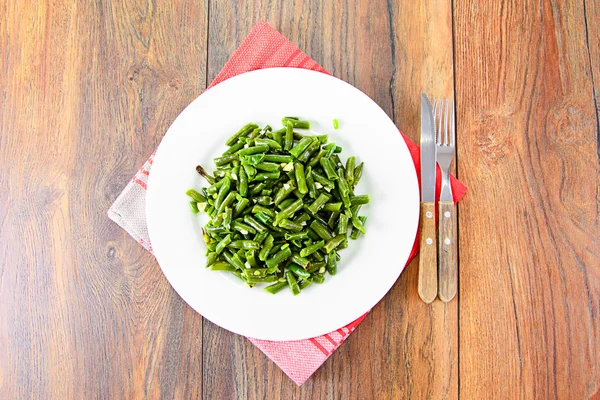 Haricots verts frits à l'ail sur une assiette blanche . — Photo
