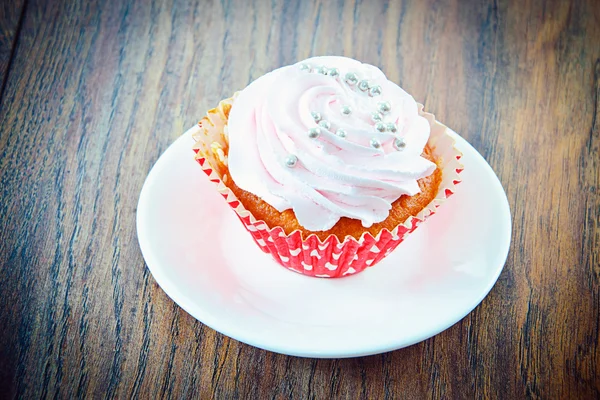 Kuchen mit Sahne, Cupcake auf holzigem Hintergrund. — Stockfoto